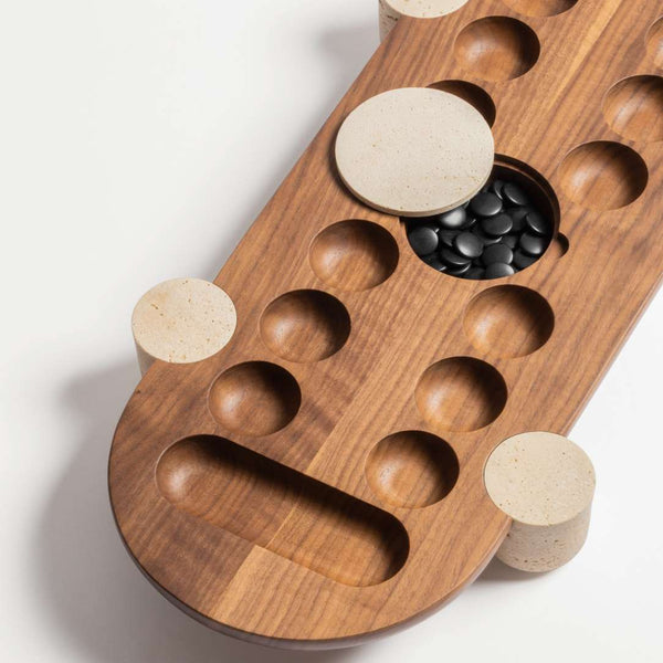 close-up of Macambo Wari game set in walnut wood with travertine marble legs and black and white Bakelite beads by Giobagnara