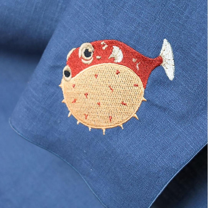 Embroidered puffer fish design on a blue fabric background
