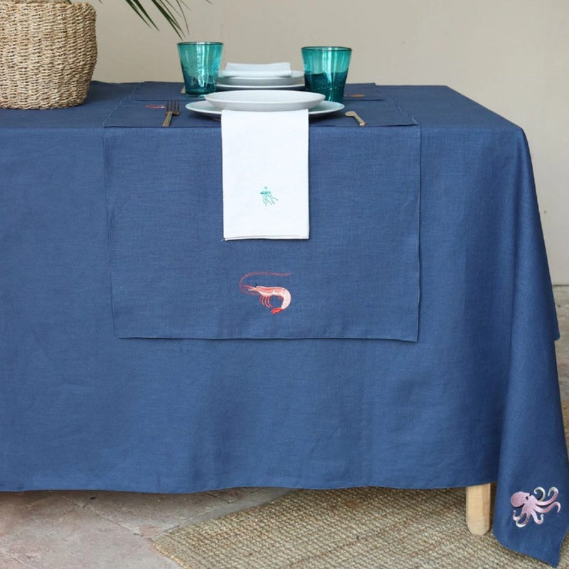 Blue tablecloth with embroidered designs on a set dining table.