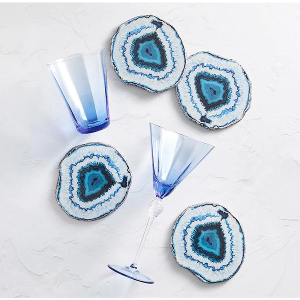 Geode-style coasters with blue and white patterns on a light surface with glasses.