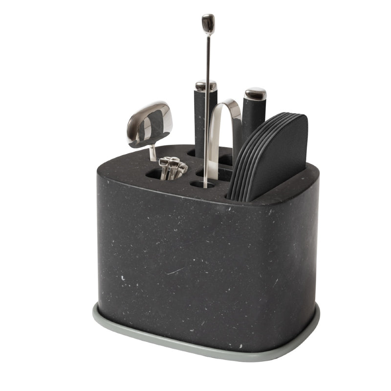 A black marble bar accessory holder with sandblasted aluminium accents, containing an assortment of stainless steel bar tools, including a corkscrew, cocktail picks, bottle opener, knife, ice tongs, and a mixing spoon.