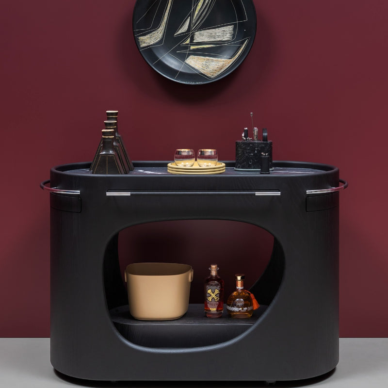 Black bar cart with drinkware against a dark red background