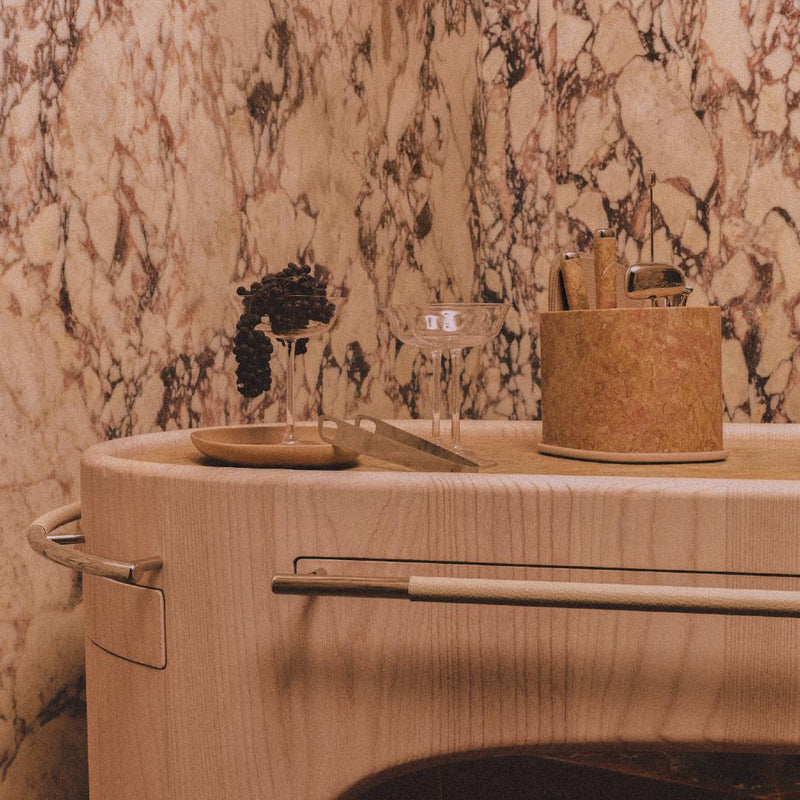 Styled Maris bar accessories set by Kelly Wearstler x Giobagnara with marble base yellow, stainless steel tools, and leather coasters