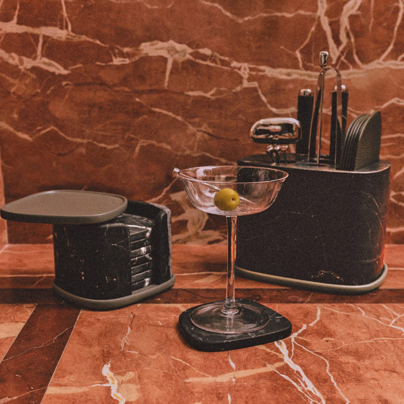 Styled counter with Maris bar accessories set by Kelly Wearstler x Giobagnara with marble base in black, stainless steel tools, and leather coasters