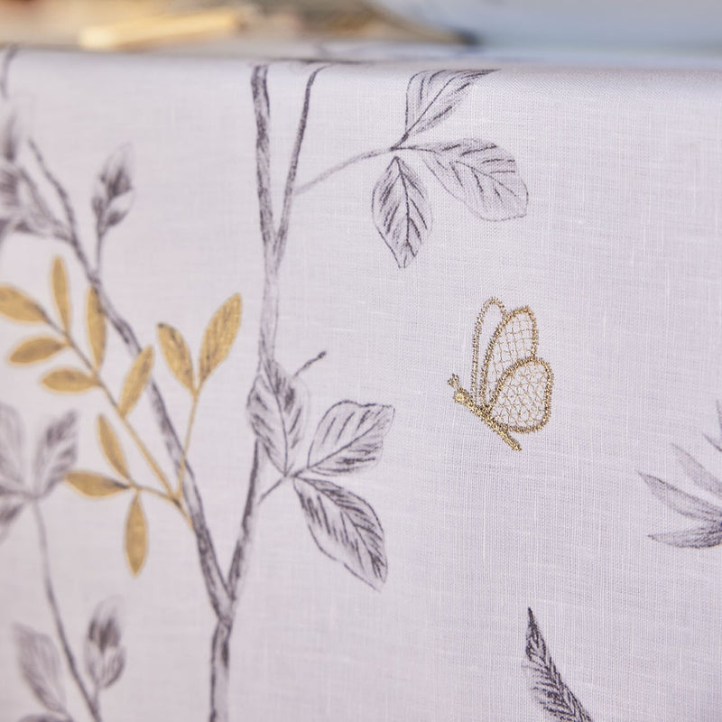 Close-up of white linen tablecloth with embroidered butterfly and flowers