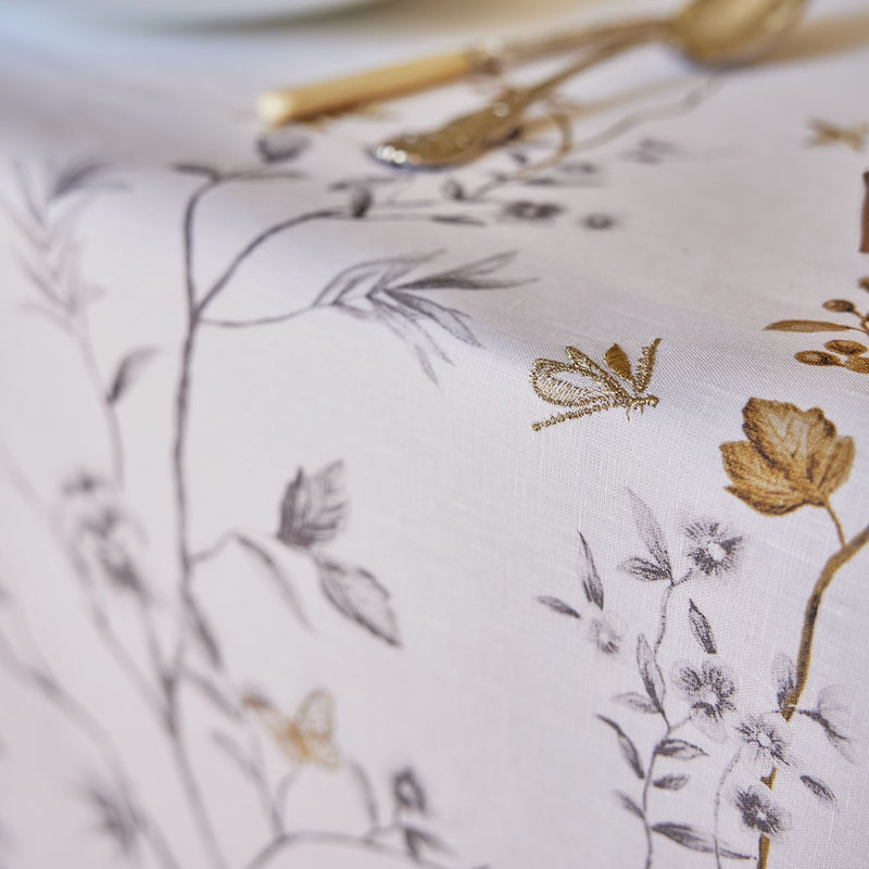 Close-up of an embroidered butterfly on a white tablecloth with tress