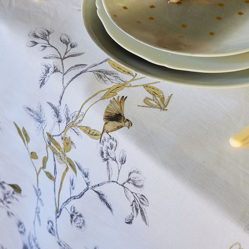 close-up of white linen tablecloth with embroidered bird and tree