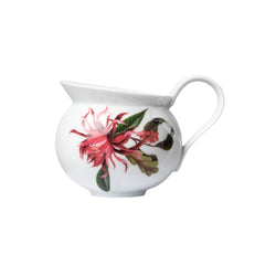 A white porcelain creamer with a floral pattern, featuring pink and red flowers and green leaves, with a handle on the side.