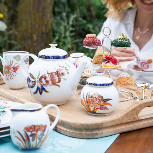 Tea set with floral designs on a wooden tray outdoors