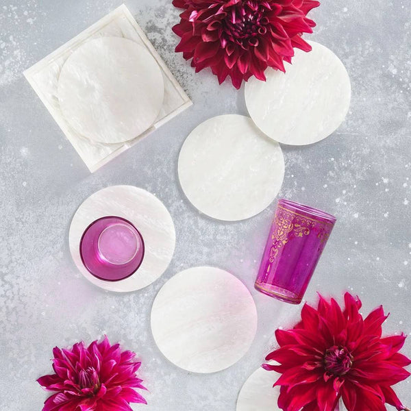 styled Mirage coasters in iridescent finish by Kim Seybert with red flowers on a grey surface