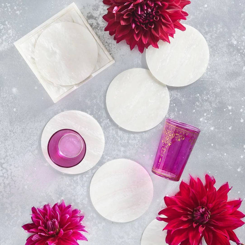 styled Mirage coasters in iridescent finish by Kim Seybert with red flowers on a grey surface