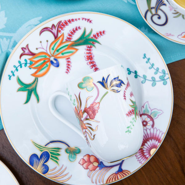 Decorative mug and plate with colorful floral patterns on a wooden surface.