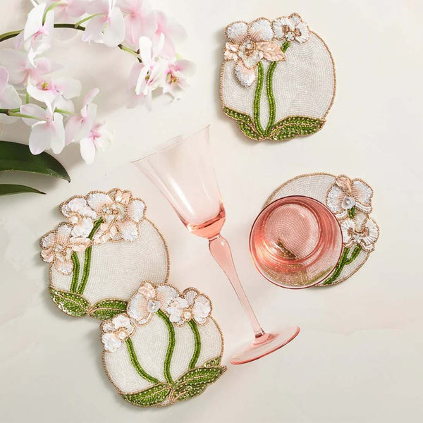 Decorative coasters with floral designs on a white surface with a glass of pink wine.