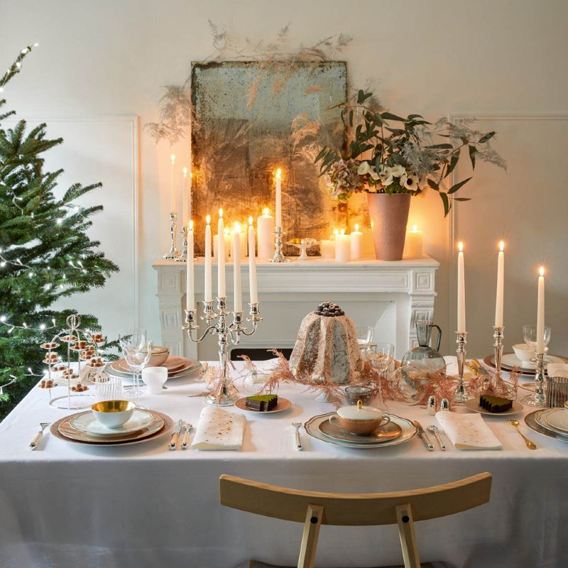 Elegant dining table setting with candles, a Christmas tree, and decorative elements.