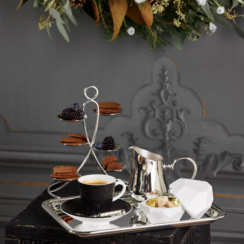 Silver-plated Petit Fours Latitude stand with six small dishes by Ercuis, ideal for serving macarons, petits fours, or desserts in a luxury setting on a tray against a decorative wall.