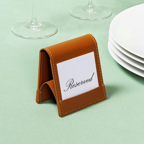 Brown leather card holder with 'Reserved' card on a light green tablecloth.