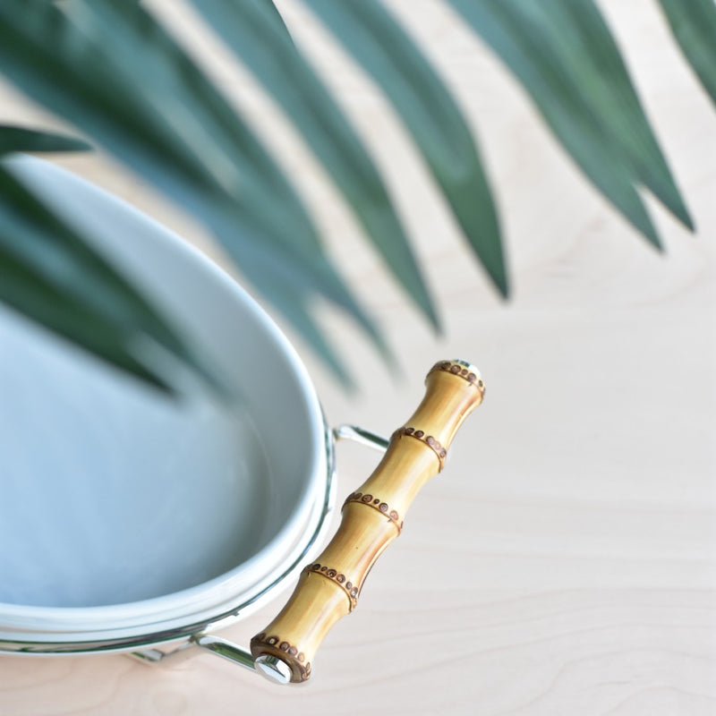 Close-up of the Porcelain oval serving dish from the Linea collection by Schiavon, featuring bamboo handles and a silver-plated stand