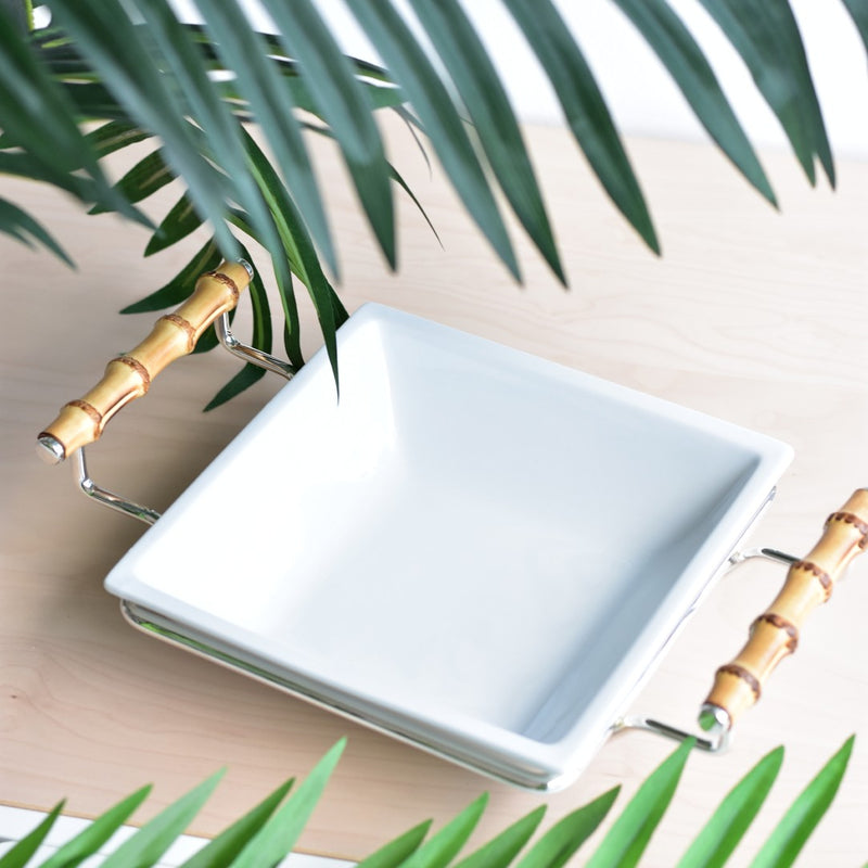 Porcelain square salad bowl from the Linea collection by Schiavon on a light wooden surface, surrounded by green leaves.