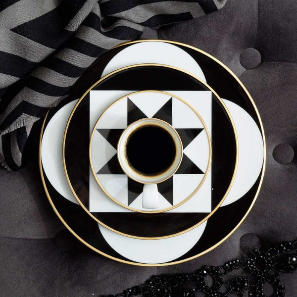 Set of black and white patterned plates with a central cup on a dark background