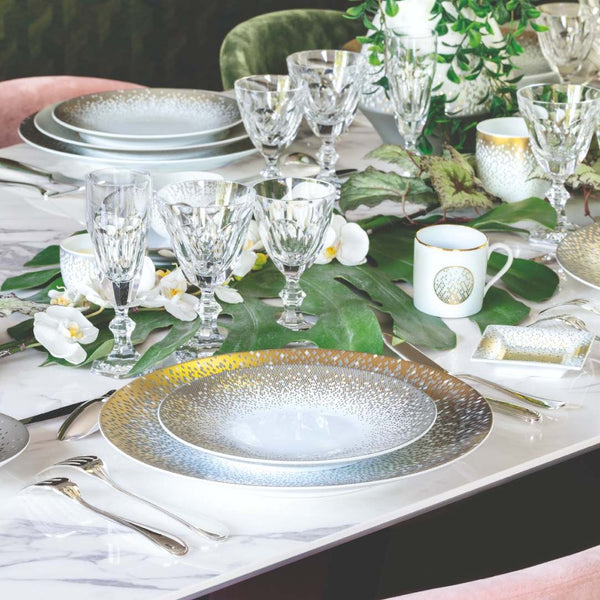Elegant table setting with plates, glasses, and cutlery on a marble surface.
