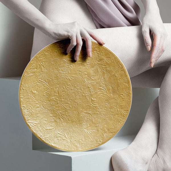 Raynaud Italian Renaissance Gold Limoges porcelain presentation plate with embossed arabesques and gold finish styled next to a woman.