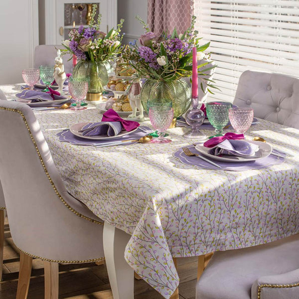 Dining table set with floral centerpieces, colorful glasses, and purple napkins.