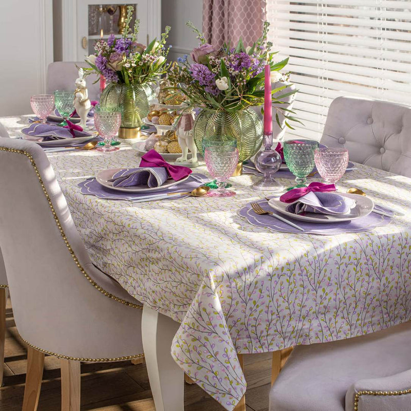 Dining table set with floral centerpieces, colorful glasses, and purple napkins.