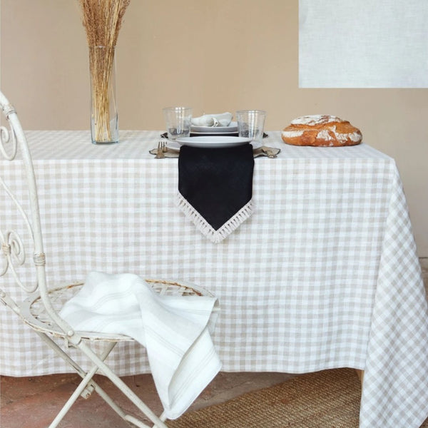 Table setting with a checkered tablecloth, plates, and bread on a neutral background