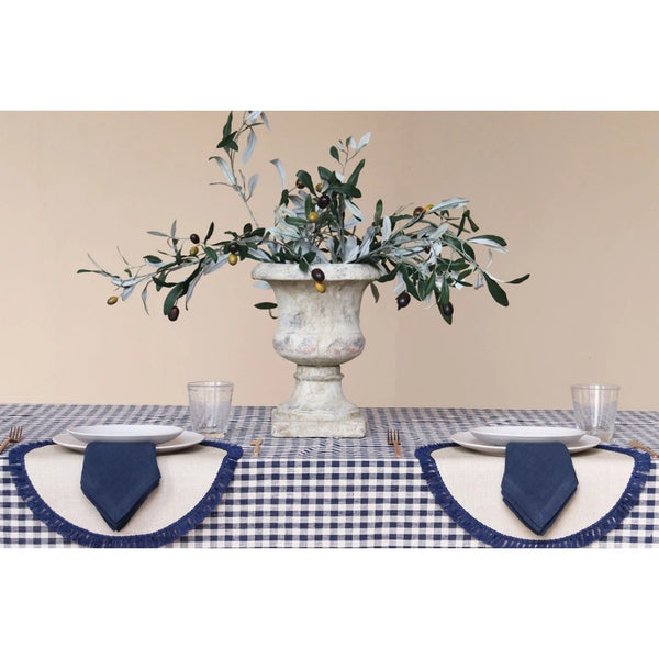 Table setting with a decorative urn and greenery on a beige background