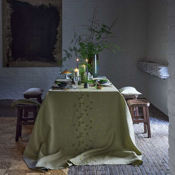 Dining table set with plates, candles, and a vase in a rustic room.