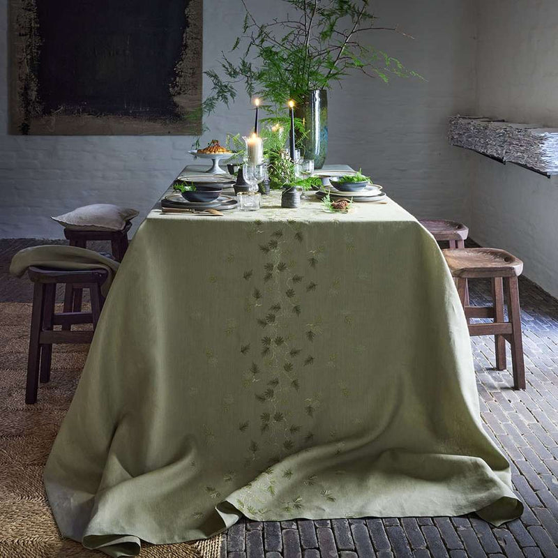 Dining table set with a green tablecloth in a rustic room.