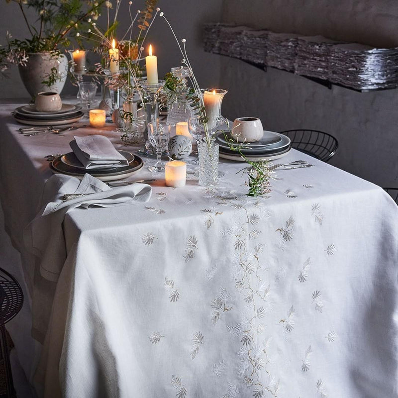 Elegant table setting with candles and floral arrangements on a white tablecloth.