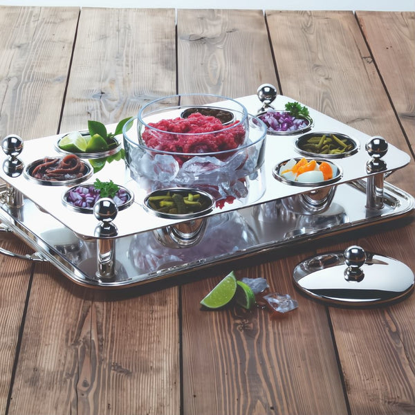 Rectangular silver-plated beef tartar set with crystal bowls by Sonja Quandt with various food items on a wooden surface