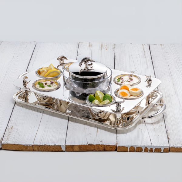 Rectangular silver-plated caviar set by Sonja Quandt with gold-gilded bowls, crystal inserts, and sturgeon-topped centerpiece on a wooden surface