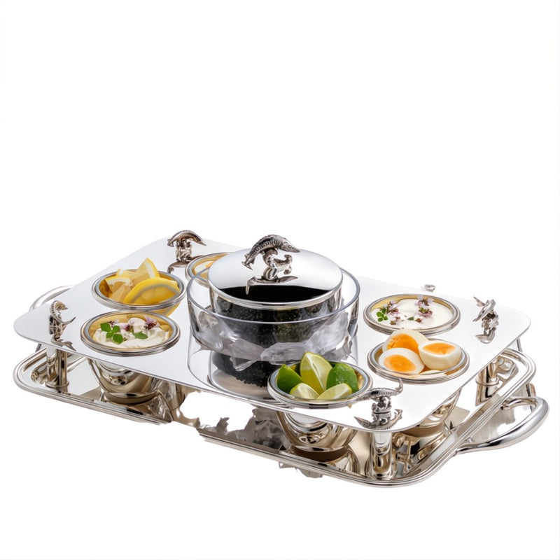 Rectangular silver-plated caviar set by Sonja Quandt with gold-gilded bowls, crystal inserts, sturgeon-topped centerpiece and garnishes on a white background.