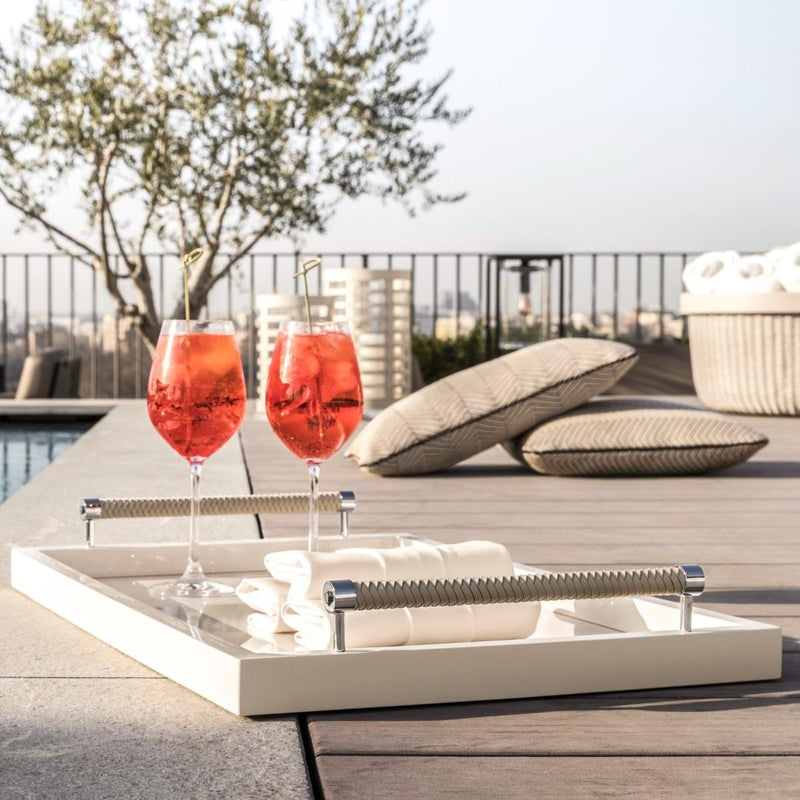Two glasses of red cocktail on a tray with outdoor setting