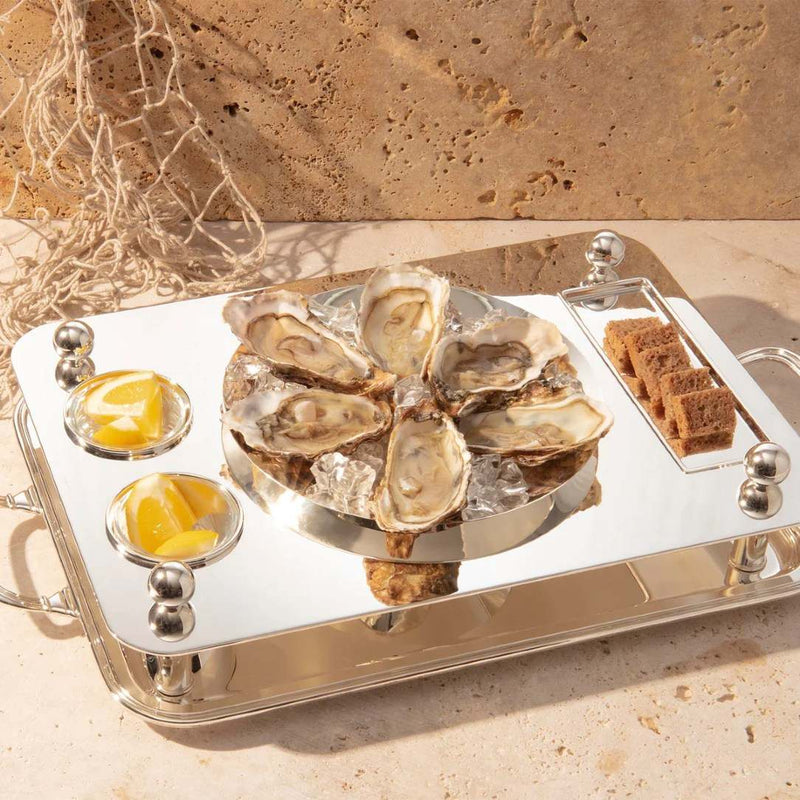 Rectangular silver-plated oyster set with 23 cm bowl by Sonja Quandt with oysters on ice, lemon wedges, and bread on a stone surface