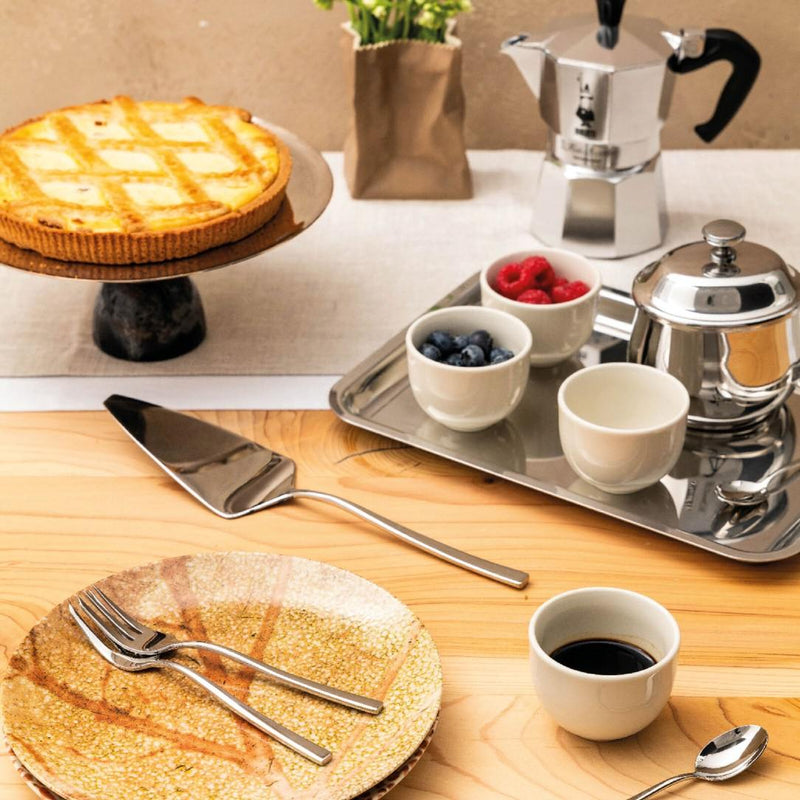 Café setting with a tart, coffee maker, and coffee cups on a wooden table.