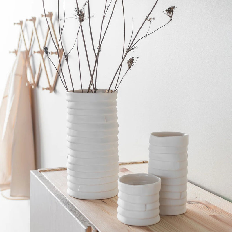 Set of white ceramic vases on a wooden surface with a neutral background