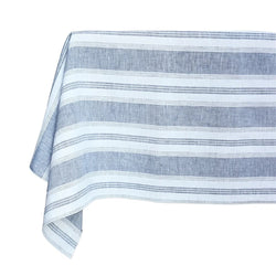 A blue and white striped linen tablecloth on a table, with an irregular stripe pattern.