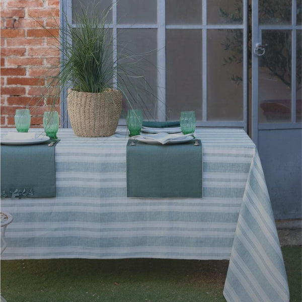 Outdoor table setting with striped tablecloth, green glasses, and potted plant.