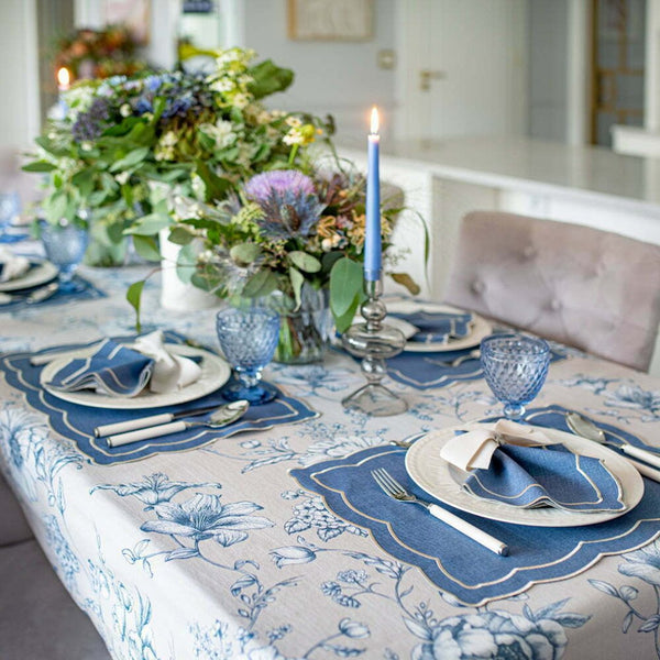 Round Blossom Blue cotton tablecloth with soft blue floral print by Roseberry Home styled in a dining room with blue glasses and candle light