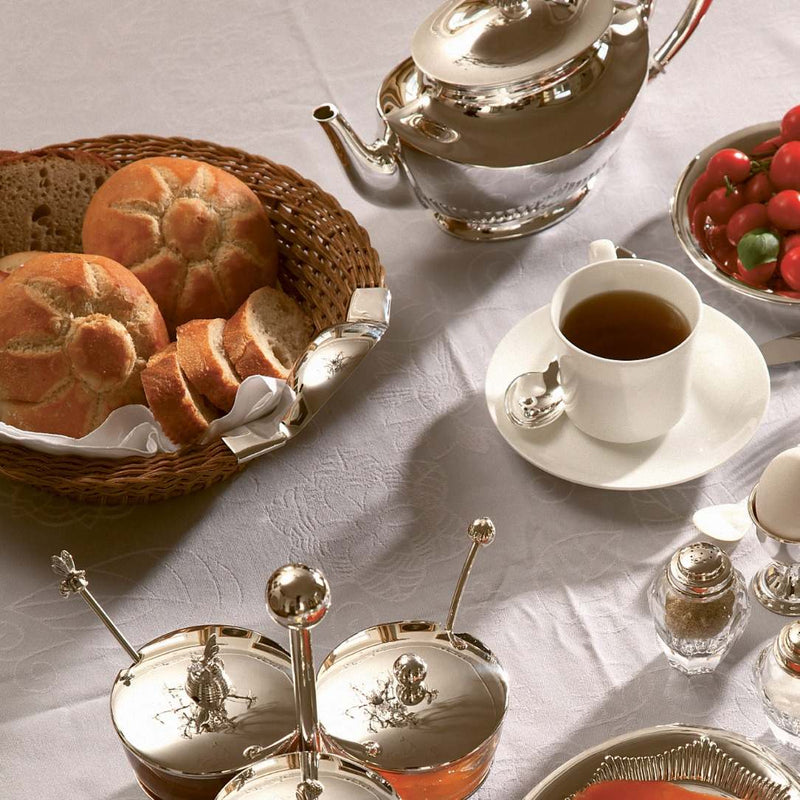 Styled breakfast table with round wicker bread basket with sterling silver handles by Sonja Quandt
