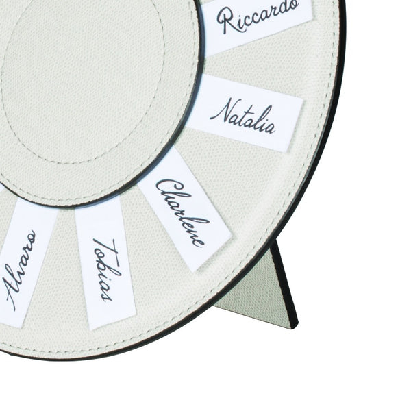 Close-up Round Leather Seating Chart Name Holder Aspen by Giobagnara in beige leather with handwritten name cards.