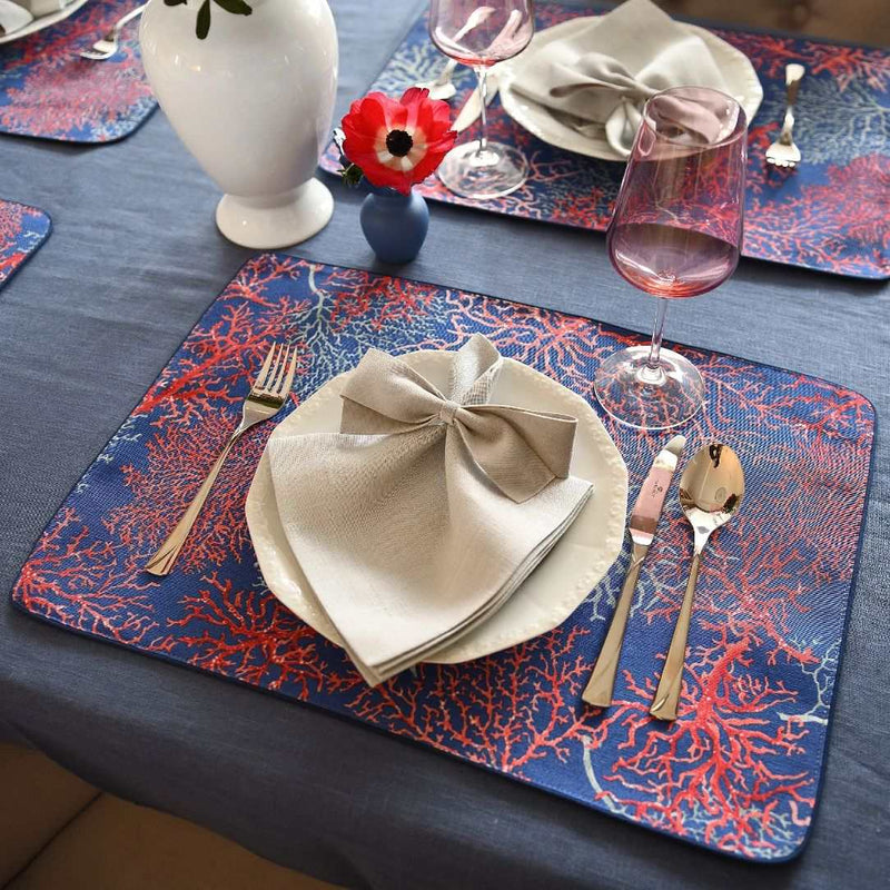 Table setting with blue placemats, beige napkins, and red wine glasses.