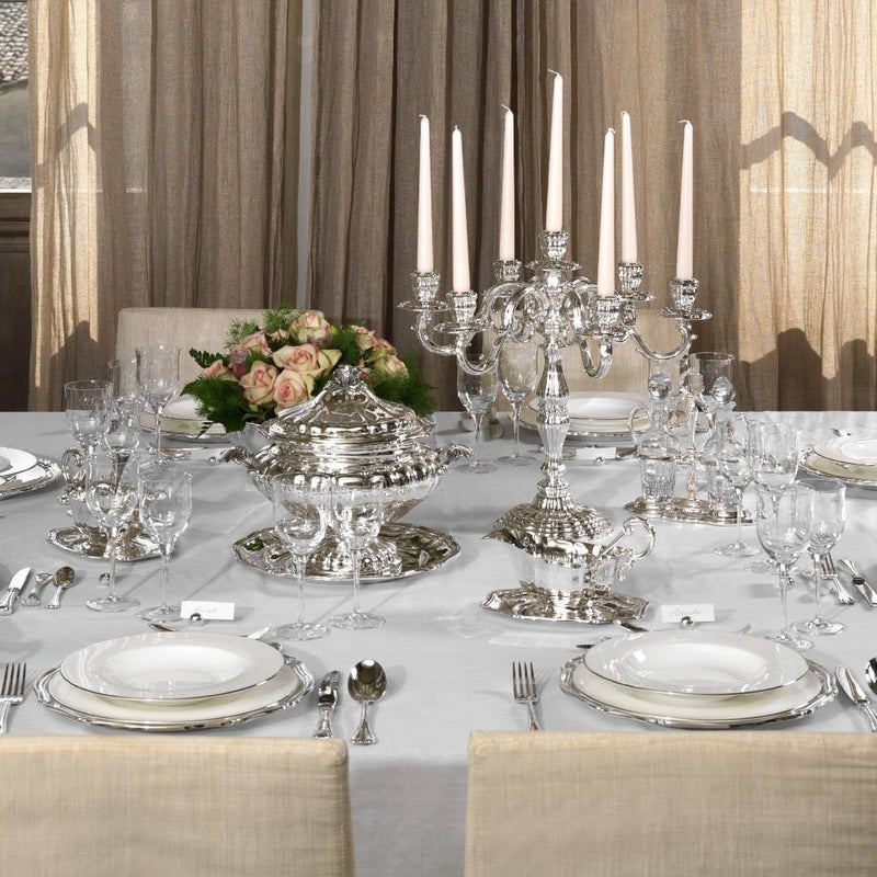Elegant dining table setting with silverware, plates, and a candelabra.
