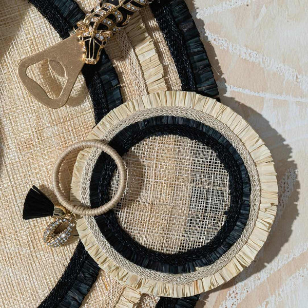 Woven straw coasters with black accents and decorative elements on a textured surface