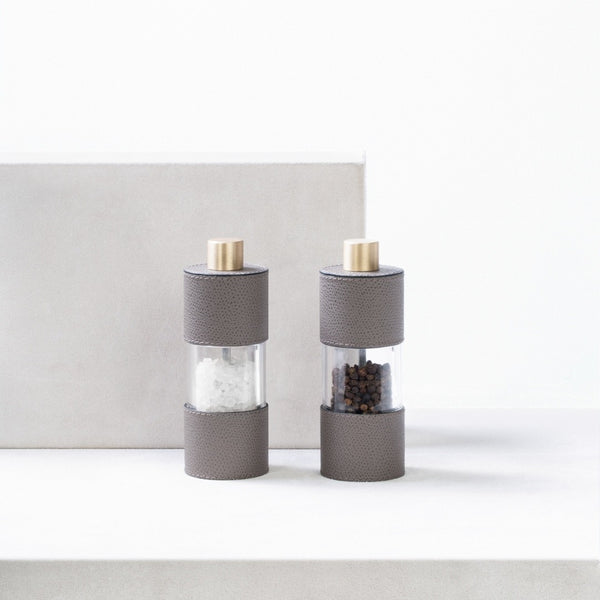 Salt and Pepper Manual Mills Set Otello Low by Giobagnara in leather and stainless steel  on a white surface.