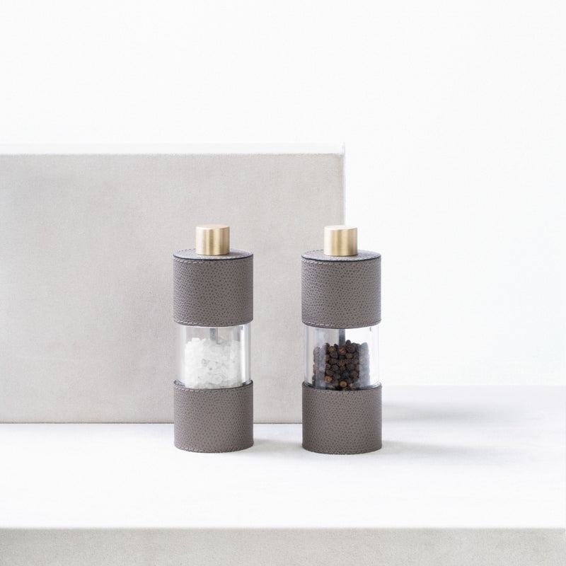Salt and Pepper Manual Mills Set Otello Low by Giobagnara in leather and stainless steel  on a white surface.