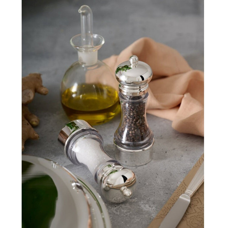 Salt and Pepper Mills Set Inglese Silver-Plated by Schiavon on a gray surface with a bottle of oil and a piece of cloth.